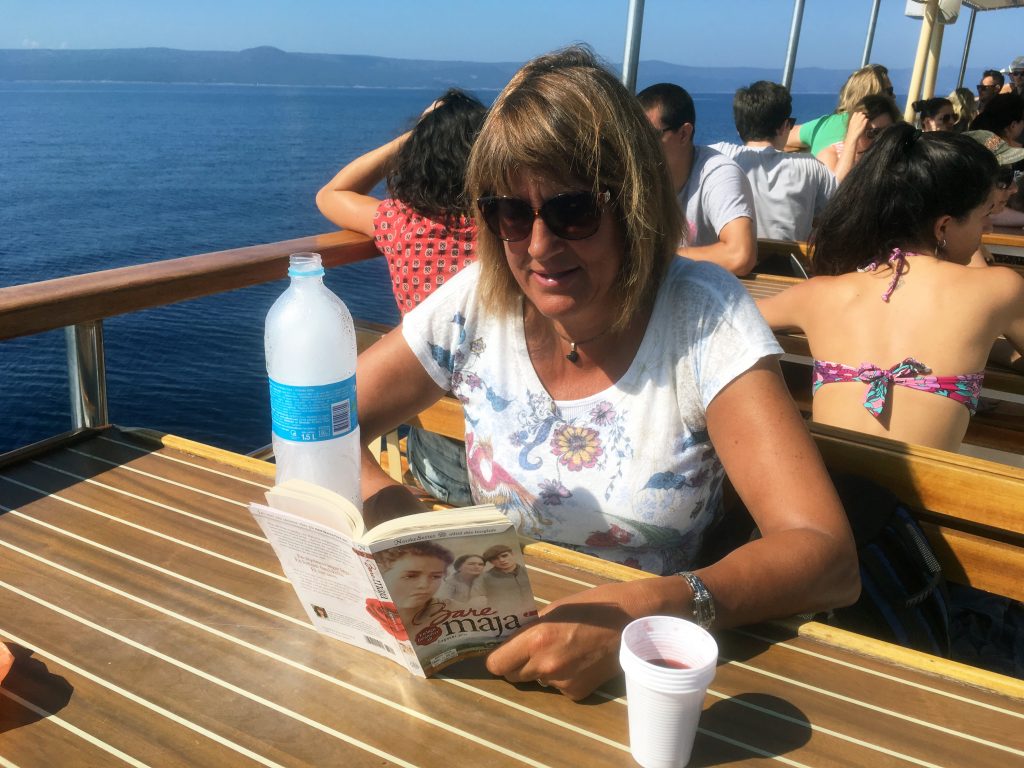 Bente fra Oslo leser seg bort. Akkurat her leser hun seg bort i Bare Maja på båten mellom Podgora og Hvar i Kroatia.