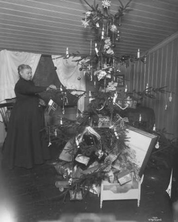 Mor i huset tenner julelysene. 1902, A.B. Wilse (foto). 